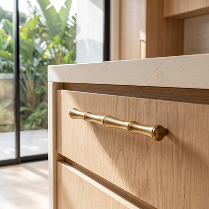 Brass handle fitted to a pale oak drawer front