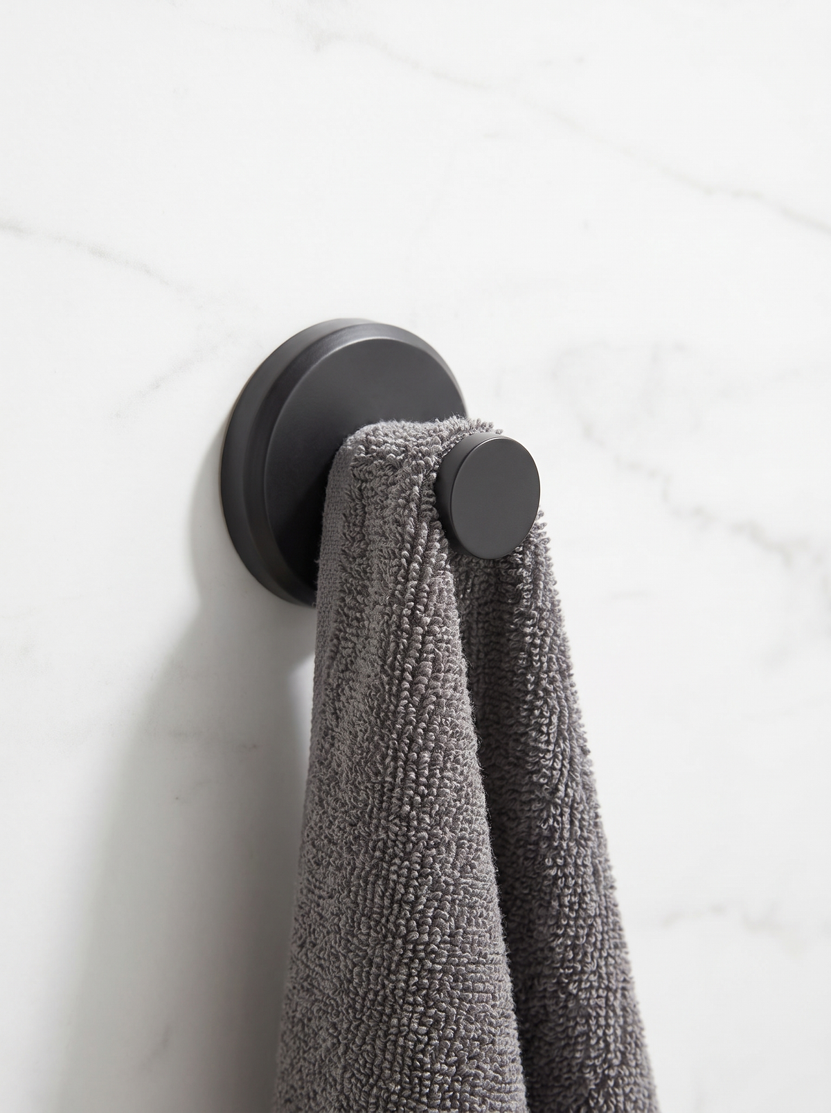Suction cup hook on a marble wall holding a hand towel